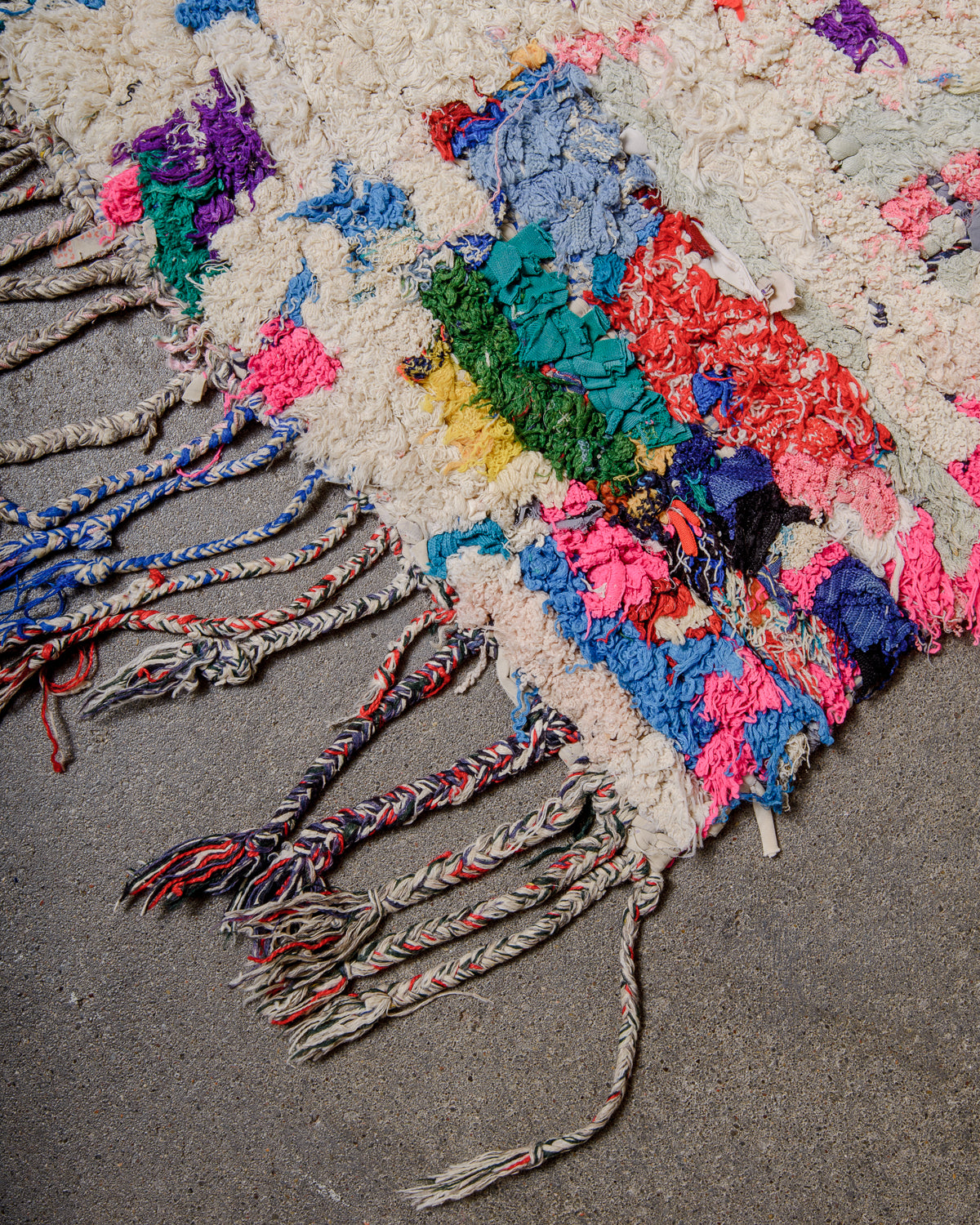 Corner of vintage Boucherouite with cotton tassels.